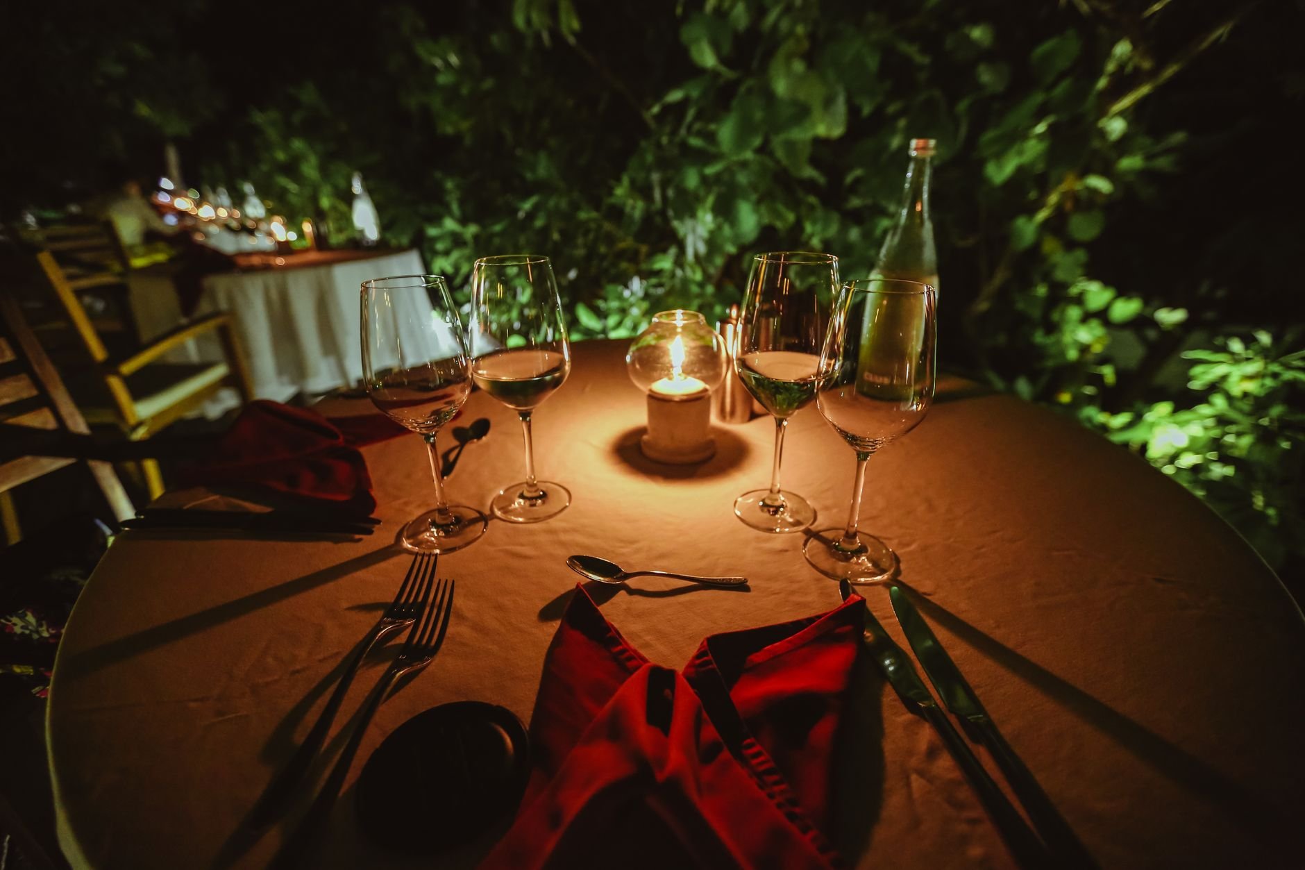 Intimate candlelit outdoor dining setting with wine glasses